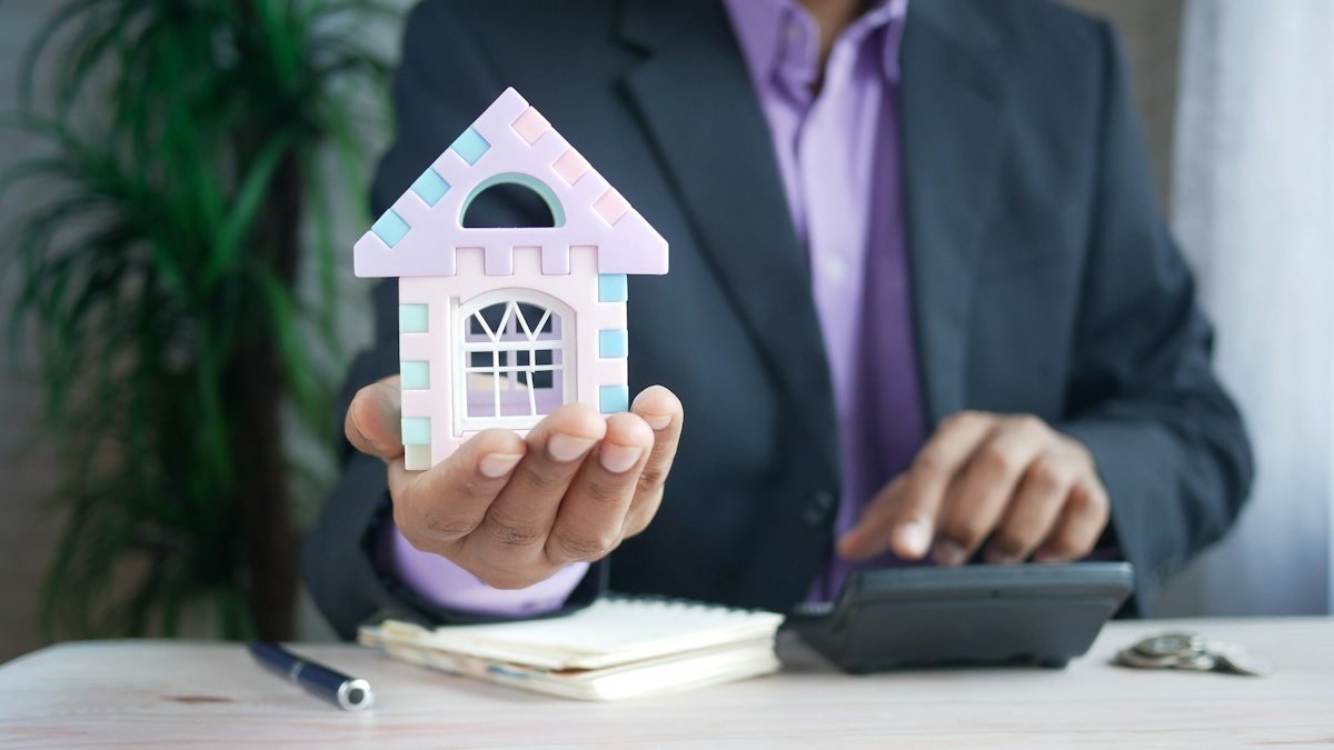 Investor analyzing a multifamily deal with a calculator and house model