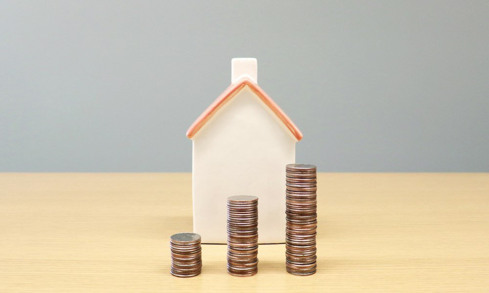 House model with stacks of coins representing multifamily NOI and cash flow